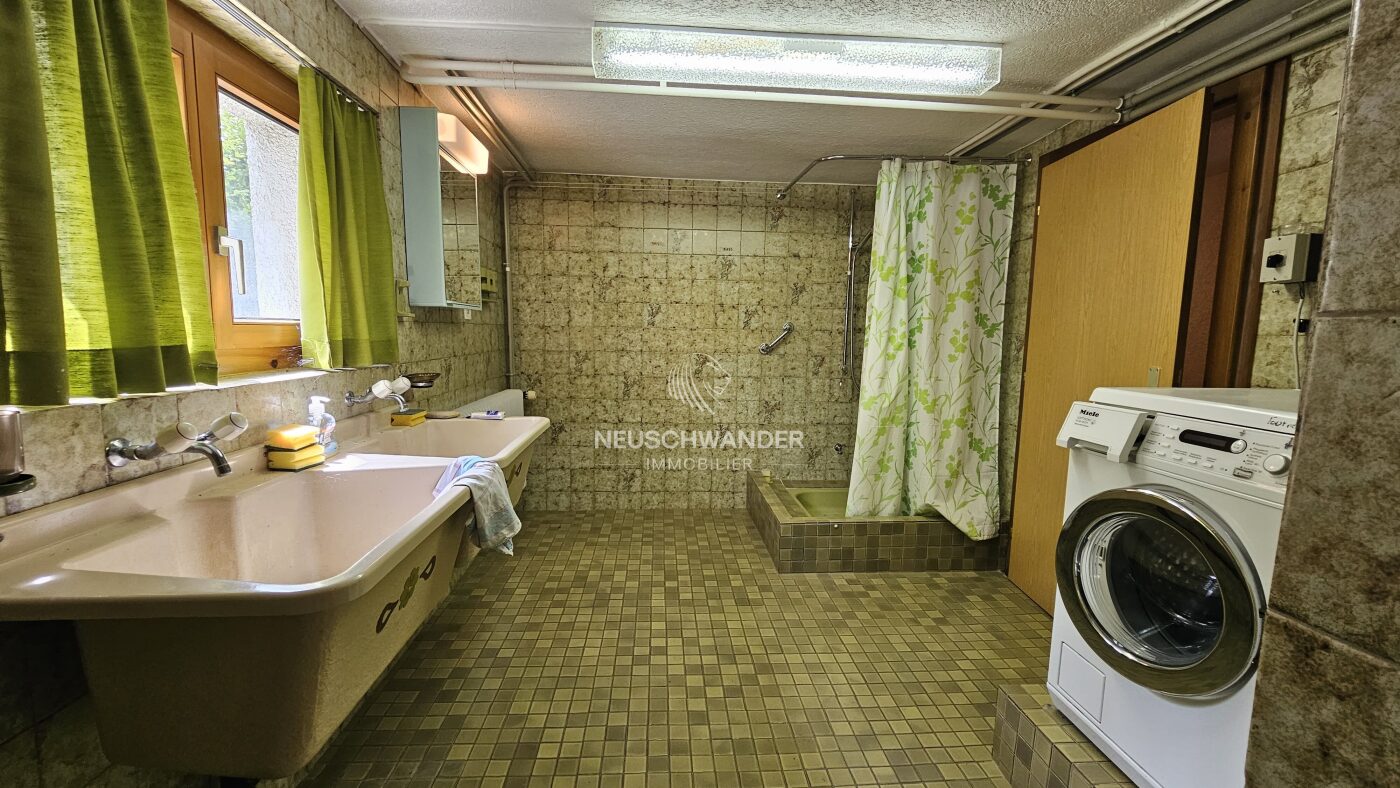 Buanderie avec douche, un double-évier, un lave-linge et une fenêtre